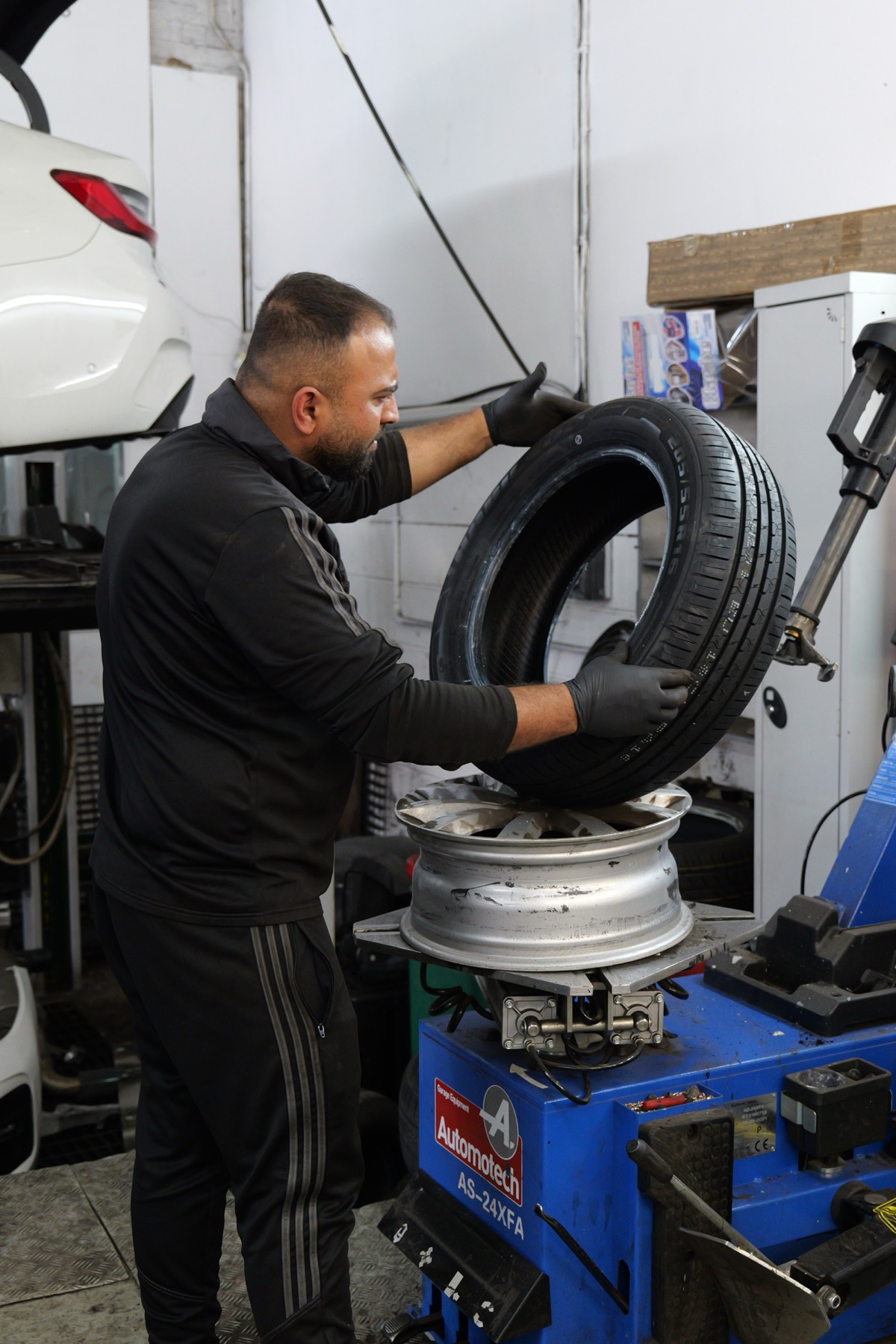 A technician fitting a tyre onto an alloy wheel at the tyre machine